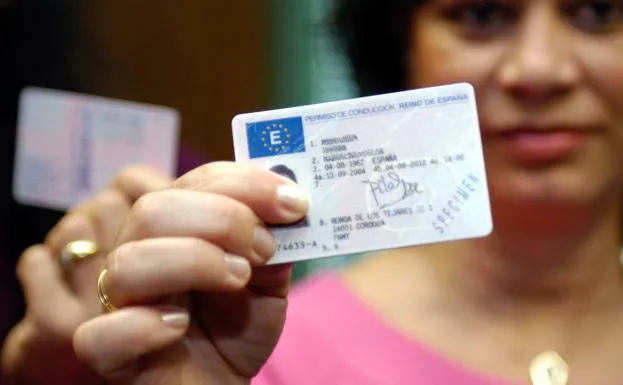 Una mujer muestra su carnet de conducir