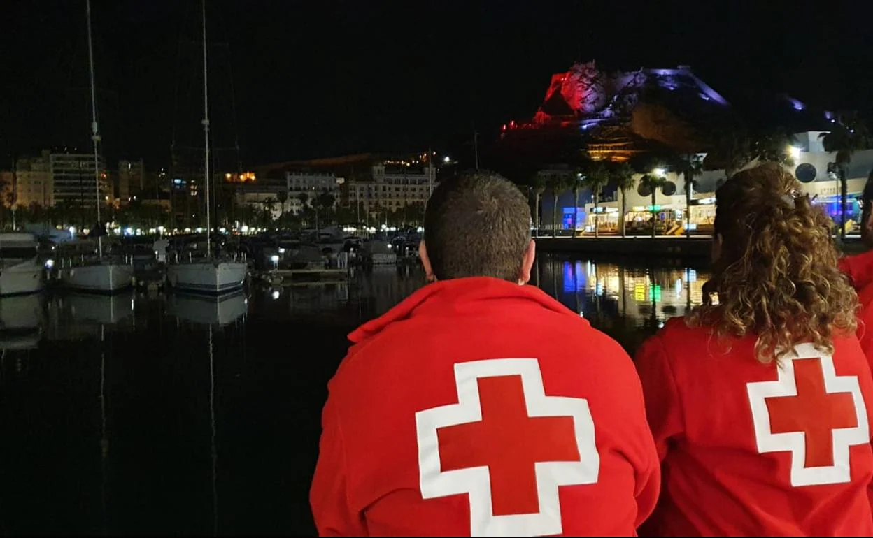 Dos miembros de Cruz Roja, con el Castillo de Santa Bárbara iluminado al fondo. 