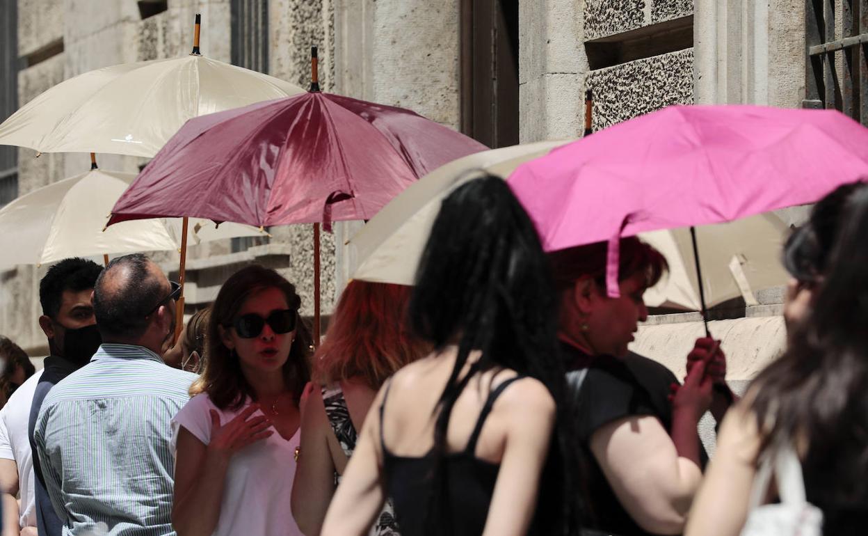 Varios jóvenes se protegen con parasoles en Valencia. 