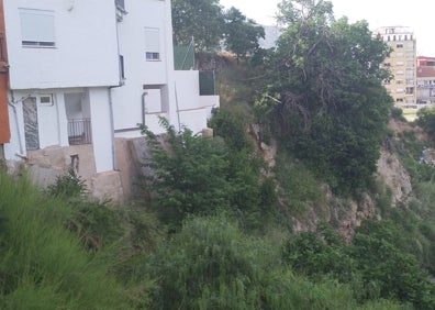 Imagen secundaria 1 - (Arriba y izquierda) Ubicación de las viviendas, al borde de una ladera. (Derecha) Estado de a calle tras la caída de hojas y lluvia.  