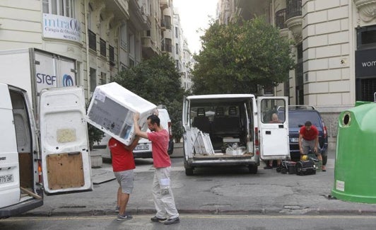 Dos operarios descargando una lavadora. 