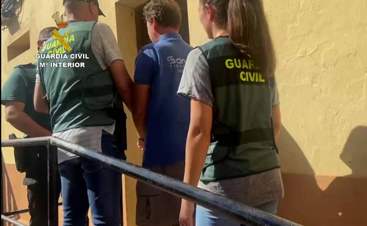 Los agentes conducen a uno de los cinco detenidos en esta operación. 