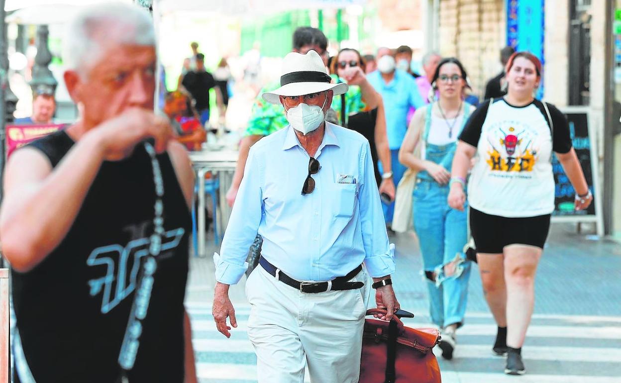 Varios viandantes portan mascarilla en una calle de Valencia. 