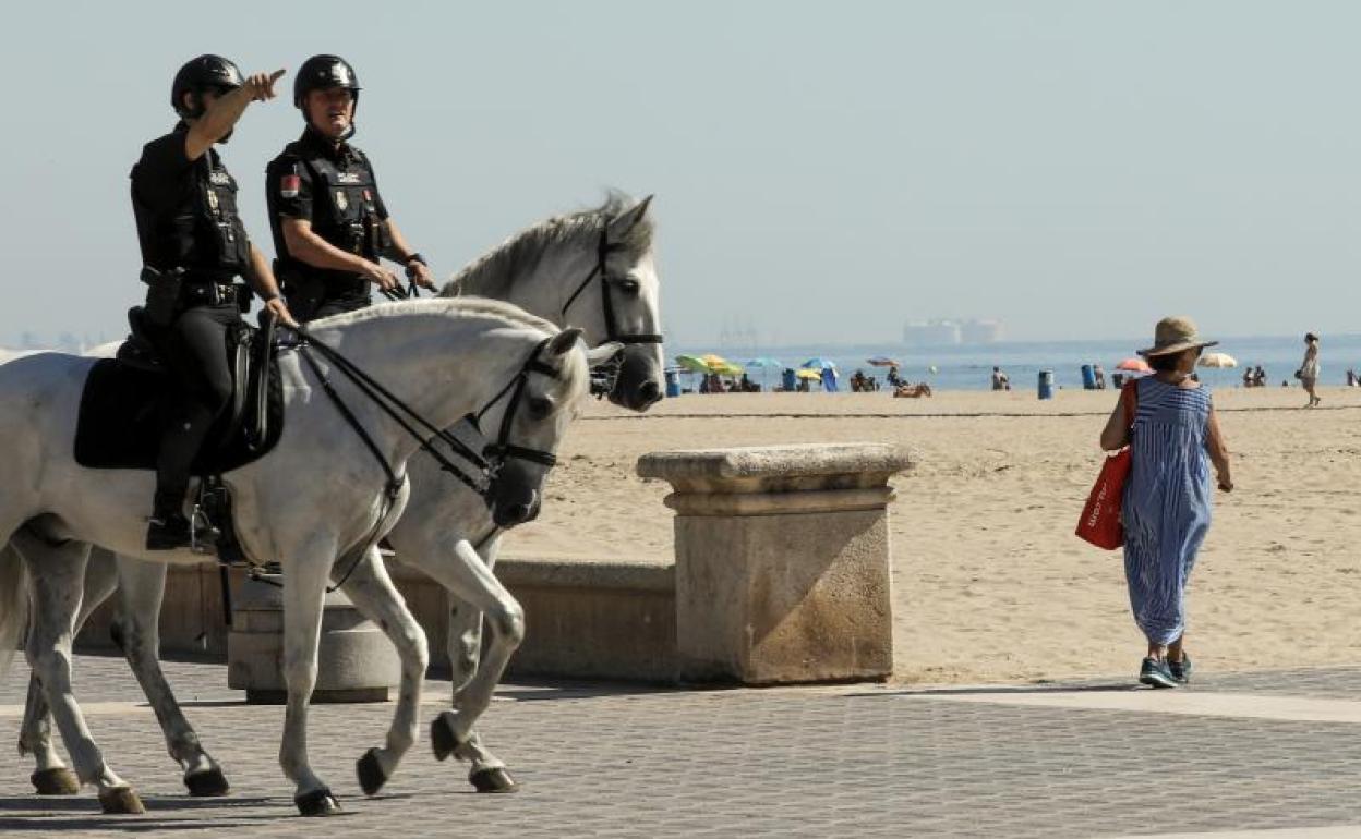 Dos agentes de la Unidad de Caballería de la Policía Nacional en el paseo marítimo de Valencia. 