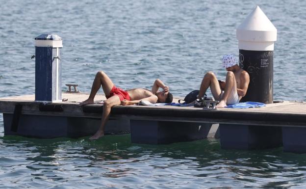 Dos jóvenes se refrescan en el puerto de Valencia.