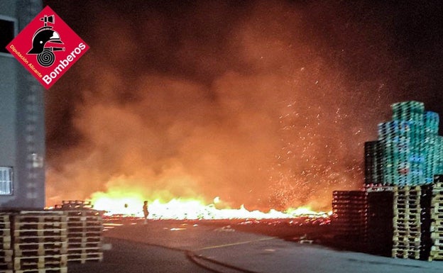 Imagen principal - Imágenes del incendio de esta madrugada en la fábrica de pallets de Elche. 