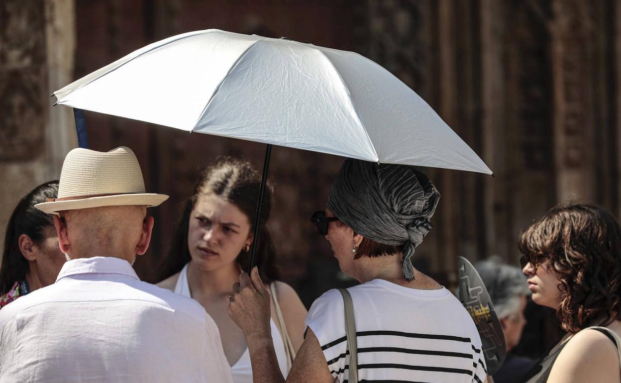 Varias personas se protegen del sol con un paraguas. 