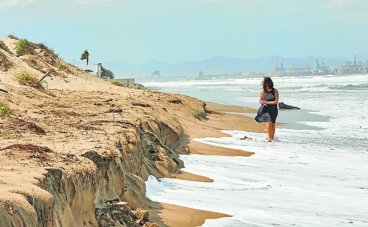 Una mujer camina junto a las dunas tras un temporal. 