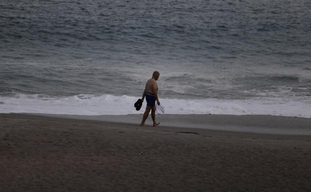 Un hombre pasea por la playa al anochecer.