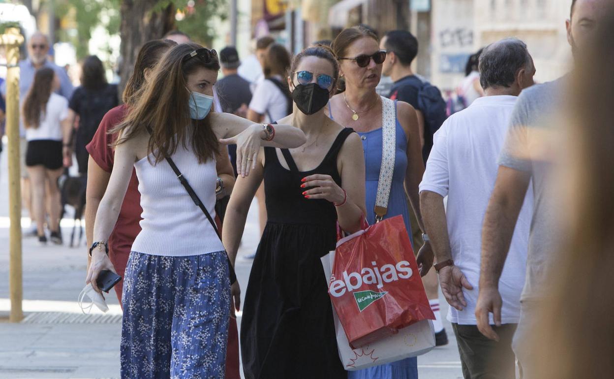 Varias personas paseando por el centro de Valencia con mascarilla.