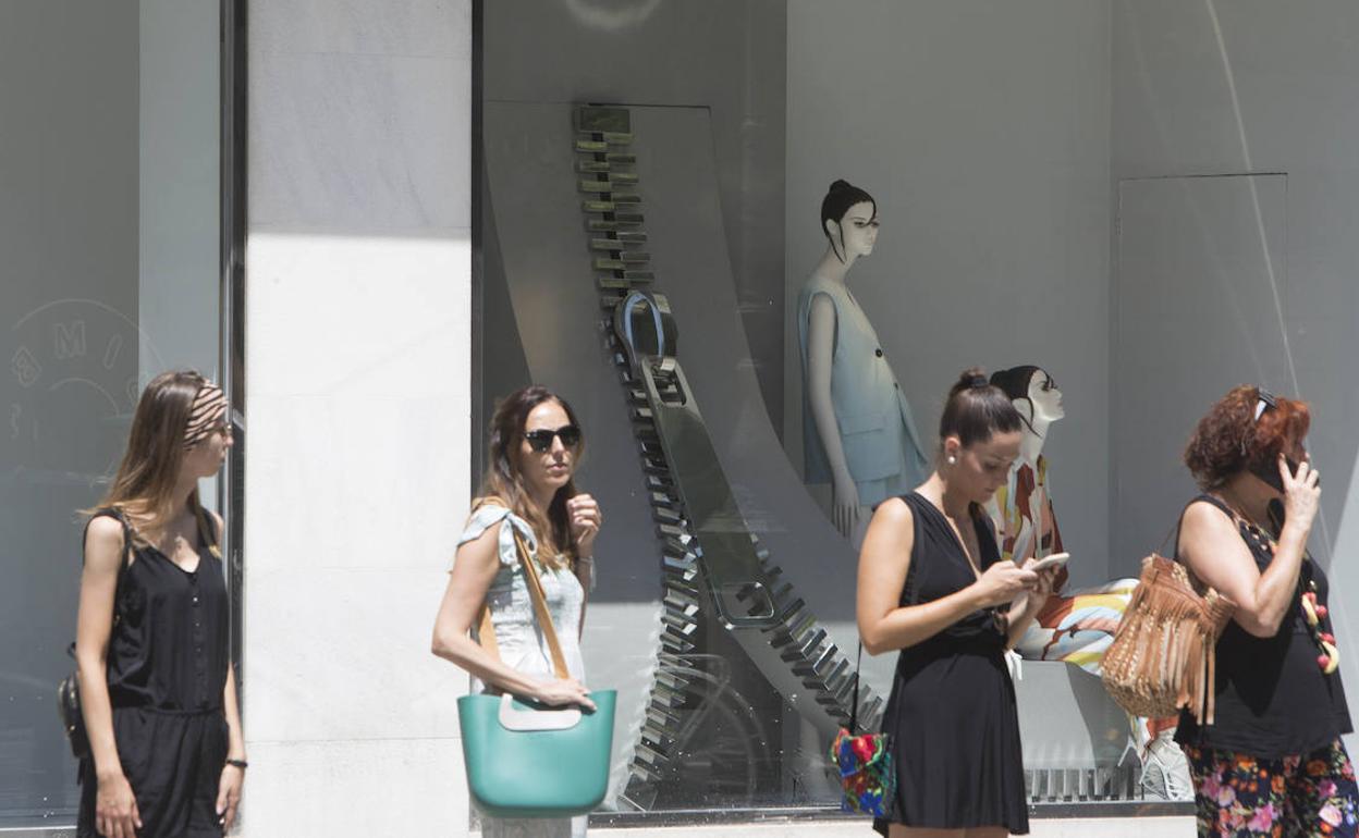 Varias mujeres esperan delante de un escaparate. 