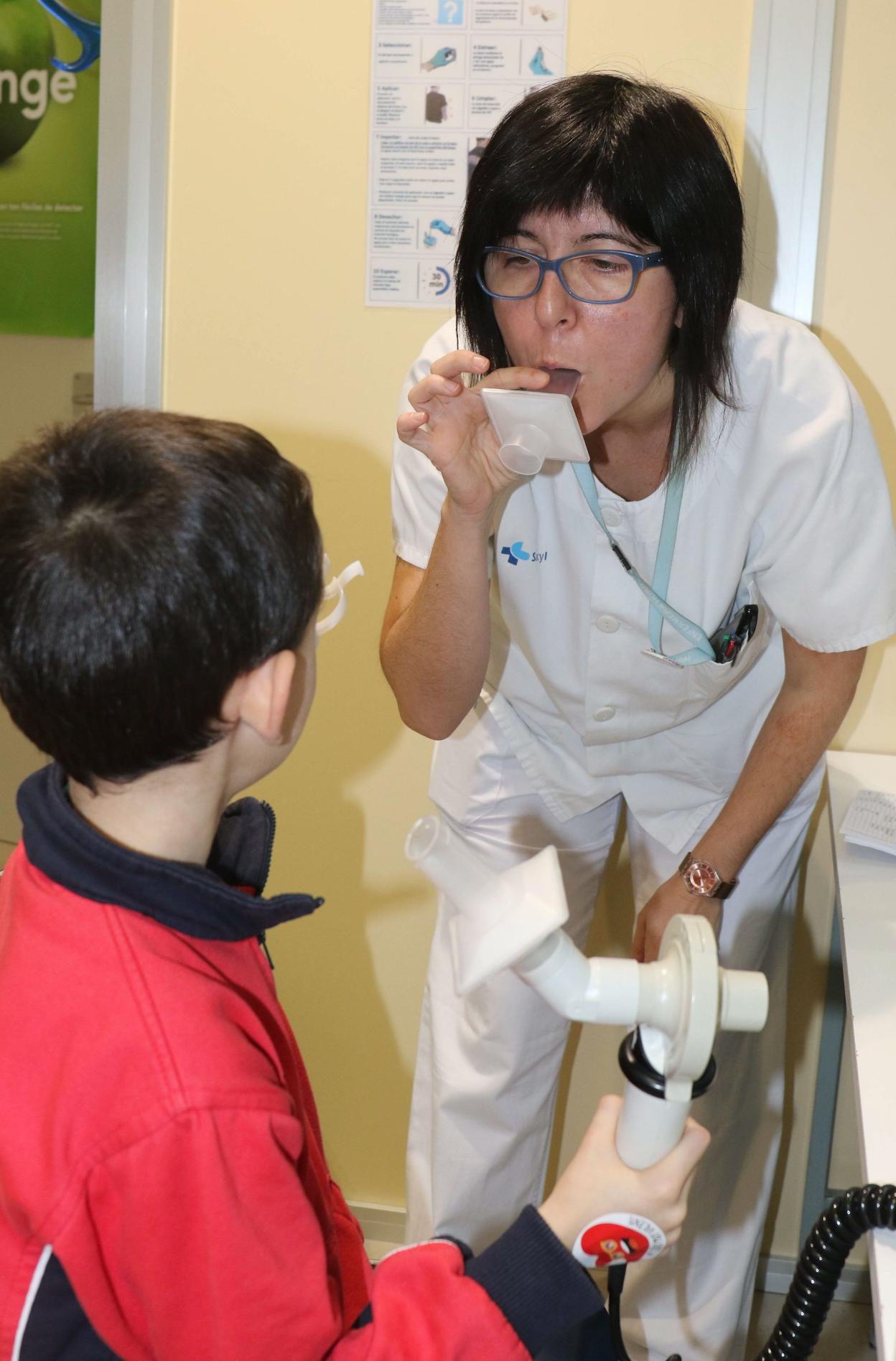 Una sanitaria muestra a un niño cómo hacer una espirometría. H. Sastre