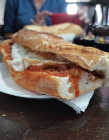 Imagen secundaria 2 - Arriba, local del bar Júcar, lleno de fotografías de clientes. Abajo, el bocadillo de la casa, con entrecot, allioli casero, ajos tiernos y patatas a la pobre. A la derecha, bocadillo Marinero, con titaina y huevo frito.