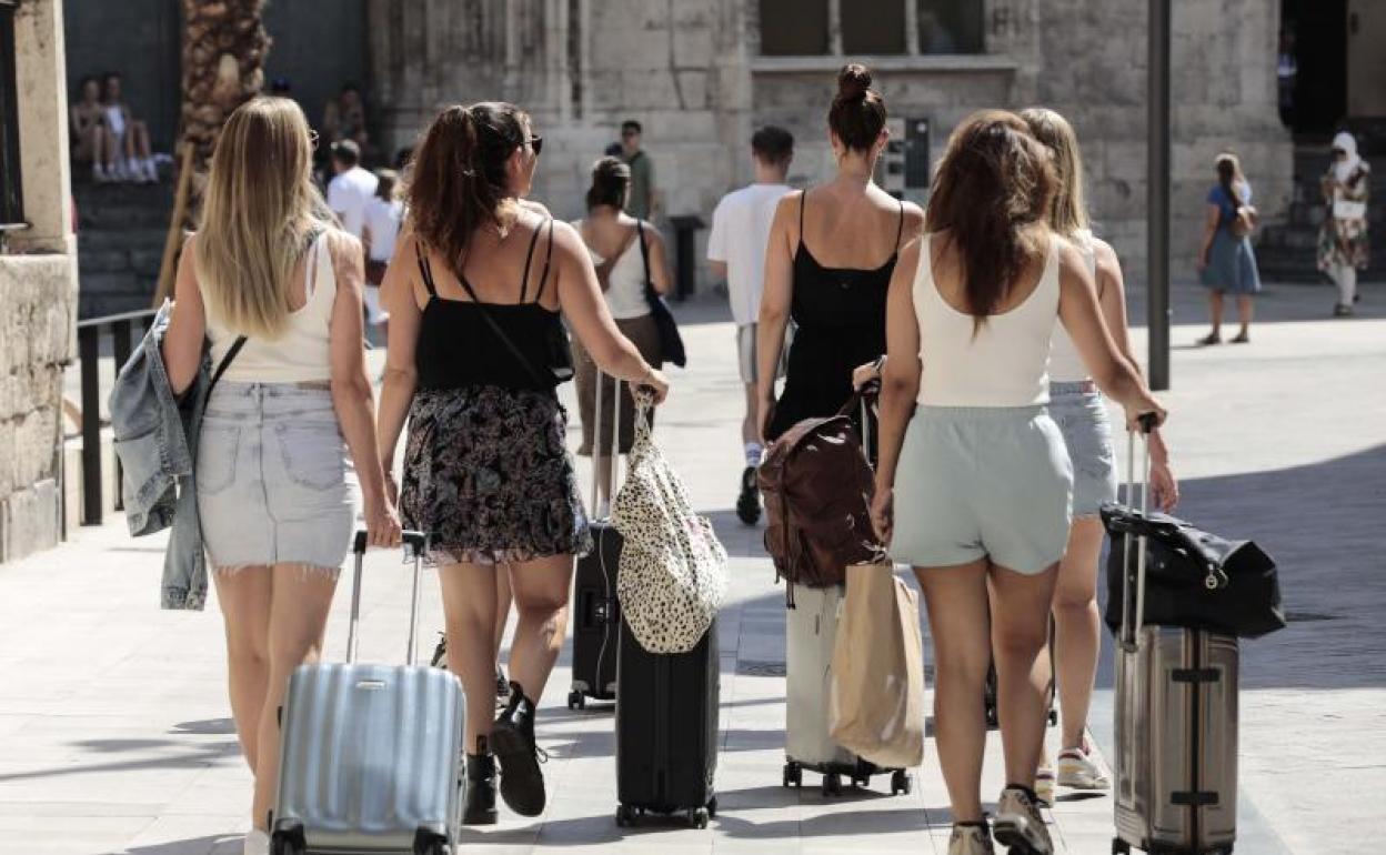 Un grupo de turista caminan con sus maletas por el centro de Valencia.