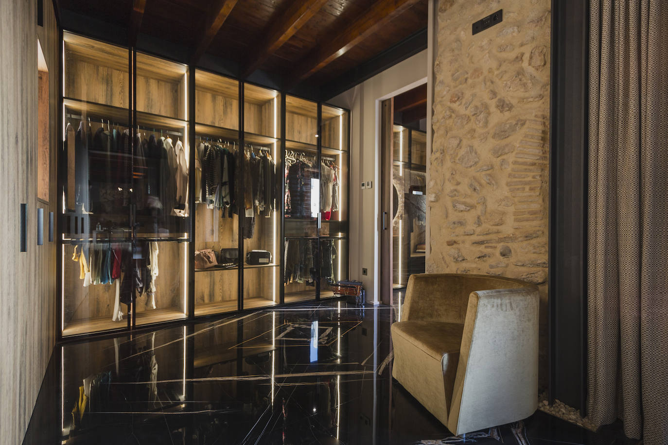 Vestidor de habitación principal, con pavimento de mármol negro y sillón Berlín de Grassoler.