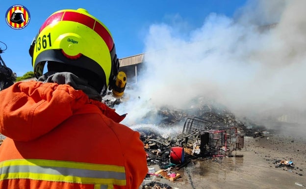 Imagen principal - Un bombero lanza agua sobre el material. 