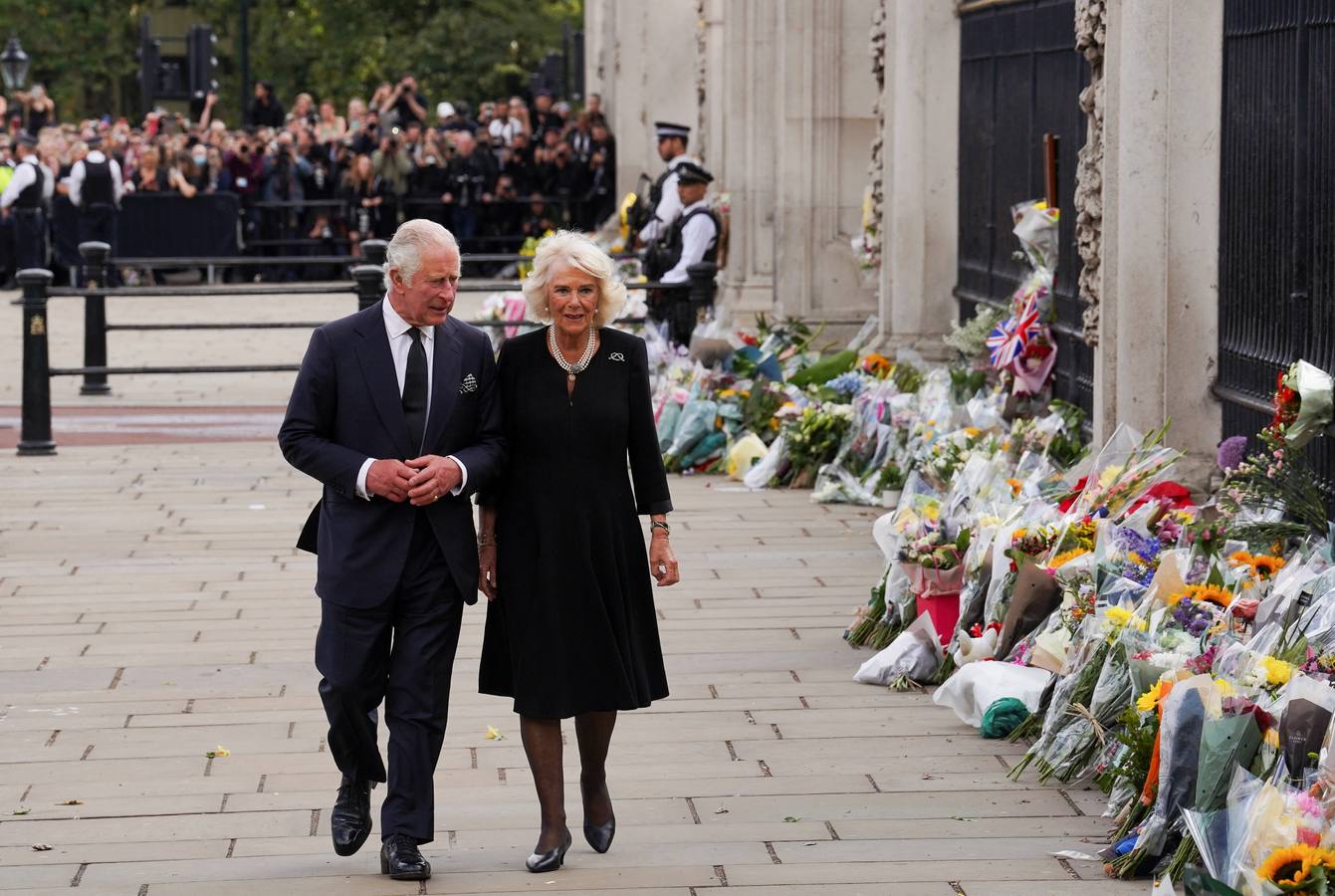 El rey Carlos y la reina Camila de Gran Bretaña caminan a lo largo de la valla del Palacio de Buckingham.