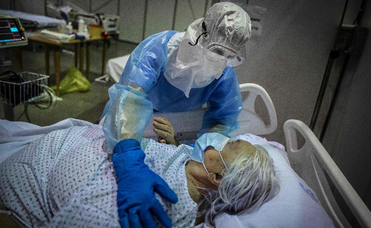 Una mujer con covid recibe los cuidados de una sanitaria.