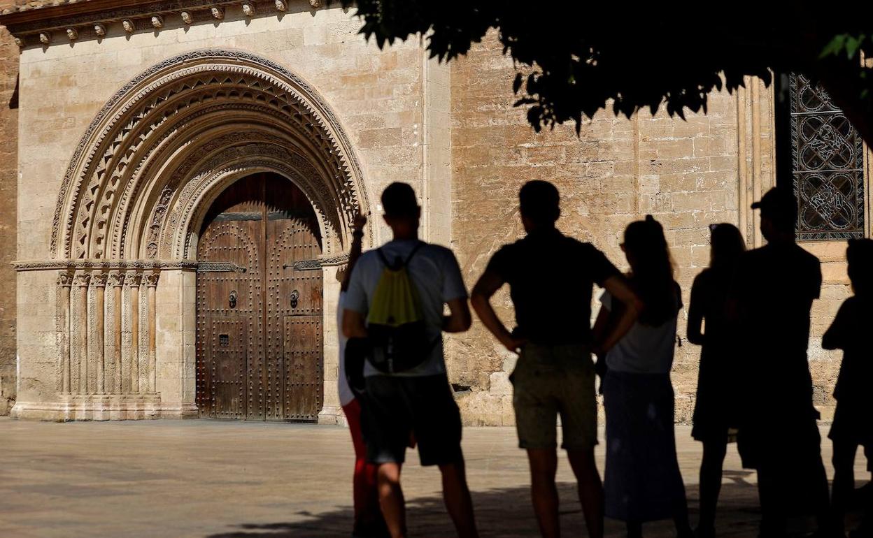 Unos turistas ante la puerta que ha sufrido el ataque. 