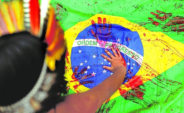 Indígenas manchan de rojo una bandera brasileña en una protesta contra la deforestación del Amazonas. 