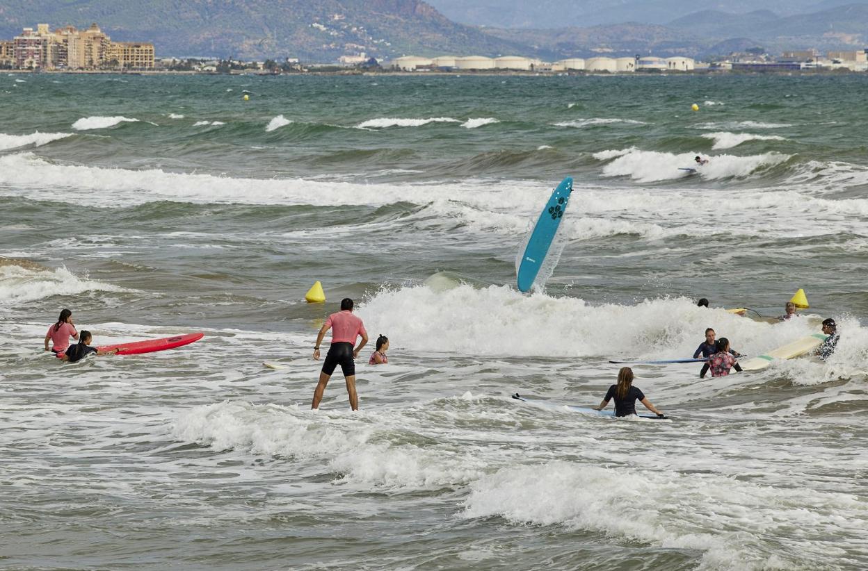 Surfistas en la playa del Cabanyal este domingo, con el mar revuelto.