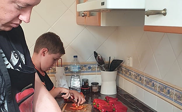 Imagen principal - Jordi y Asier, picando los ingredientes para elaborar la 'pebrera', unos pimientos acabados y Jordi introduciendo el relleno. 