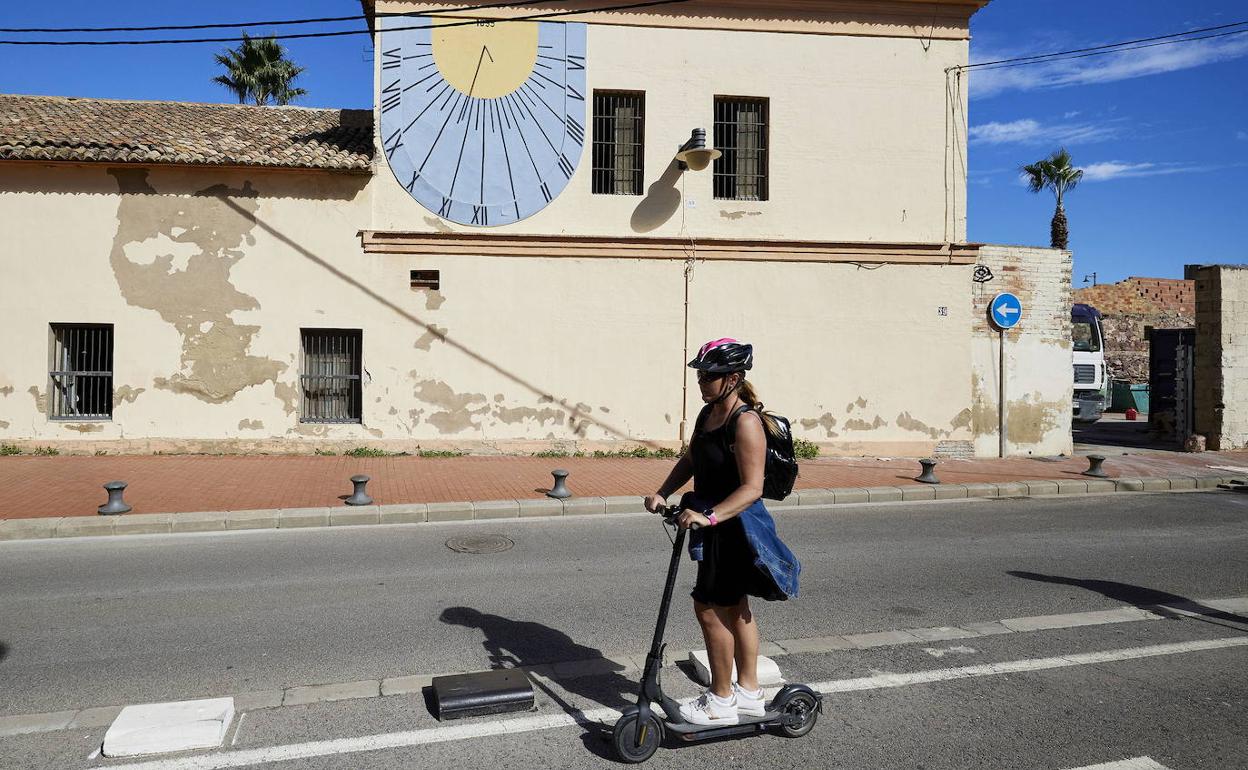 Una joven pasa en patinete eléctrico por delante de la Casa dels Bous. 