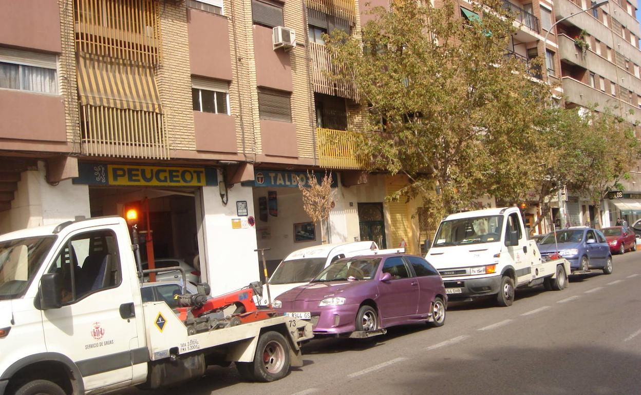 Grúas con coches enganchados junto a una base municipal. 