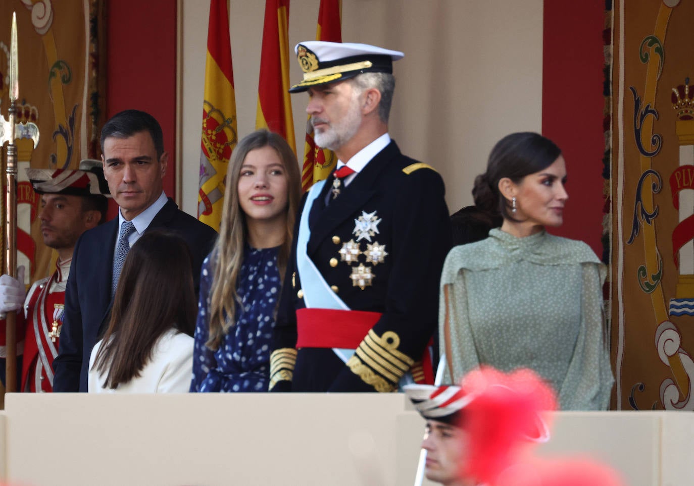 La reina opta por un vestido de gasa en verde con lunares blancos de la firma española Vogana. Se trata del modelo Nanda, de la colección del año 2021, con un precio de 265 euros. En la pieza de silueta fluida y cintura marcada destacaban las originales mangas, con una abertura que dejaba ver discretamente sus torneados brazos y formadan una suerte de capa. Menos discretos son los espectaculares pendientes de perlas australianas que le regaló don Felipe hace más de una década, con los que completó el estilismo.