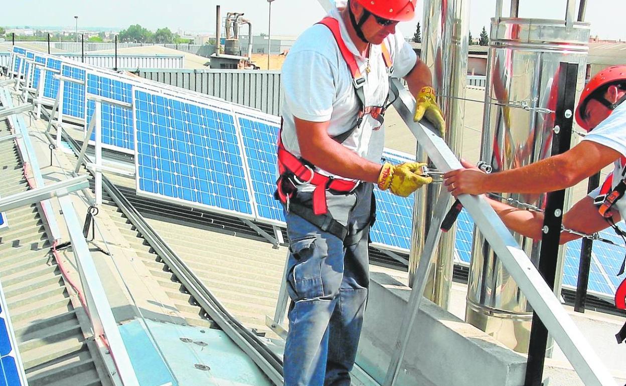 Operarios instalando placas fotovoltaicas en la cubierta de un edificio.