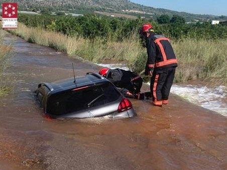 Fotos: Los bomberos rescatan a una mujer atrapada en su coche hundido en un socavón en Onda