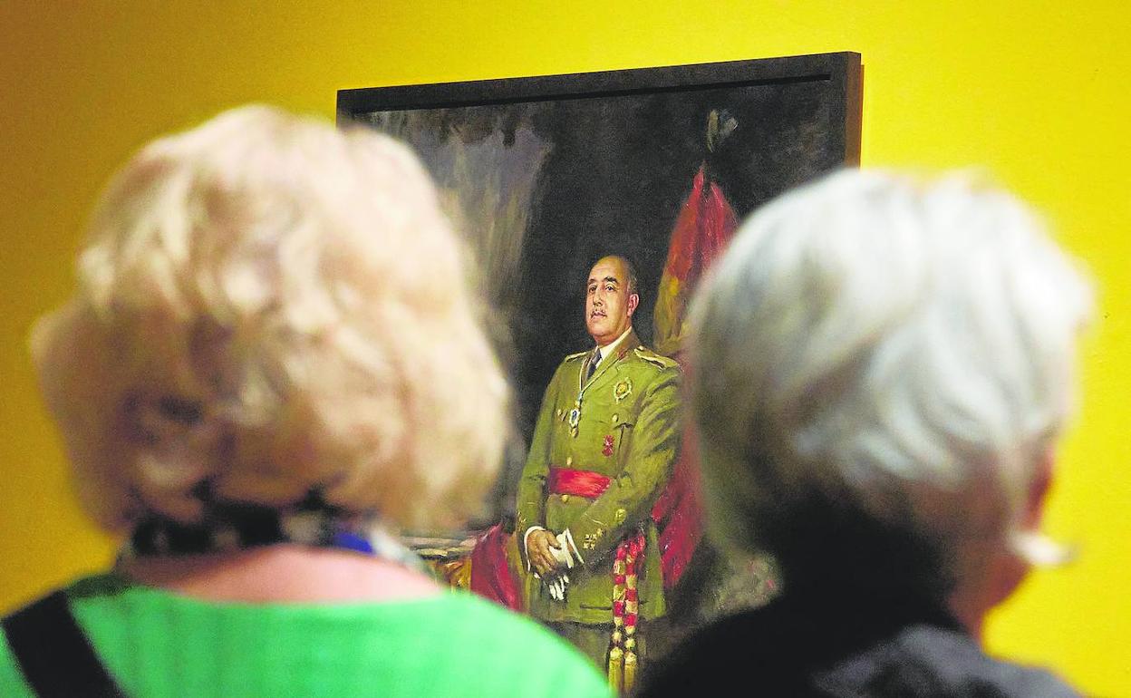 Dos mujeres contemplan el retrato de Francisco Franco, obra de José Segrelles, que se expone en la muestra. 