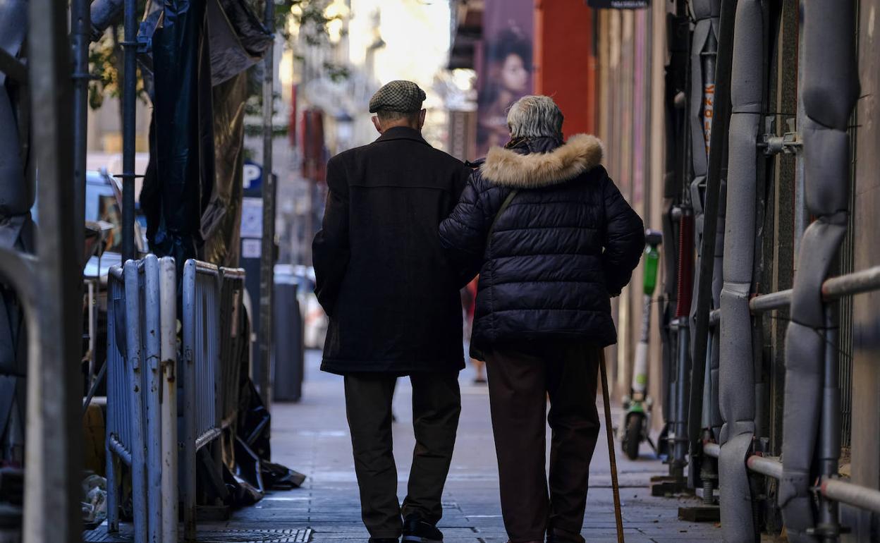 Dos pensionistas pasean juntos por la calle.