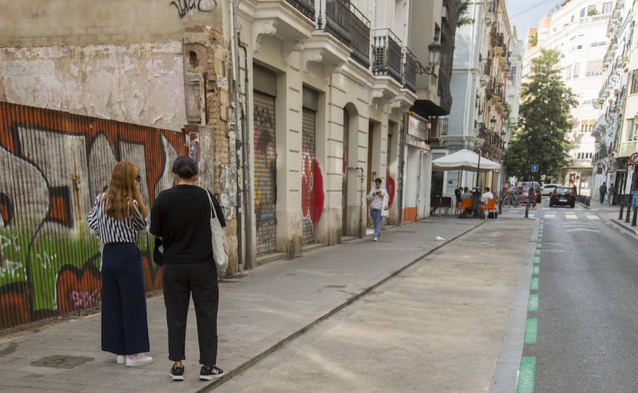 Dos viandantes junto a plaza de aparcamiento vacías en Ruzafa. 