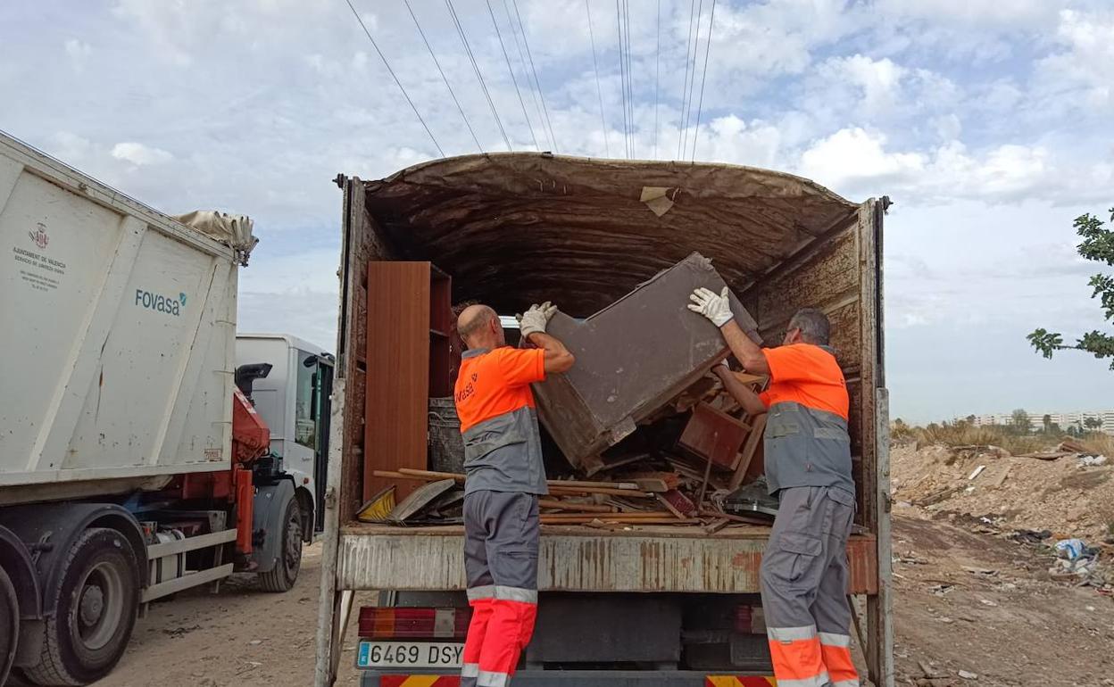 Operarios de la contrata cargando muebles abandonados en un solar.