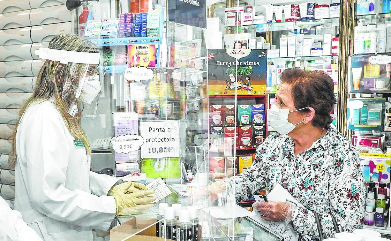 Una mujer acude a la farmacia a recoger sus medicamentos. 