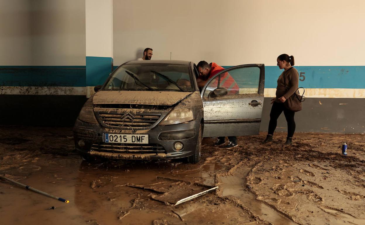 Unos vecinos de Riba-roja observan un coche en un garaje. 