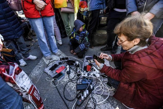 Unas personas cargan sus teléfonos con un generador en la ciudad reconquistada de Kherson, Ucrania, el 14 de noviembre de 2022.