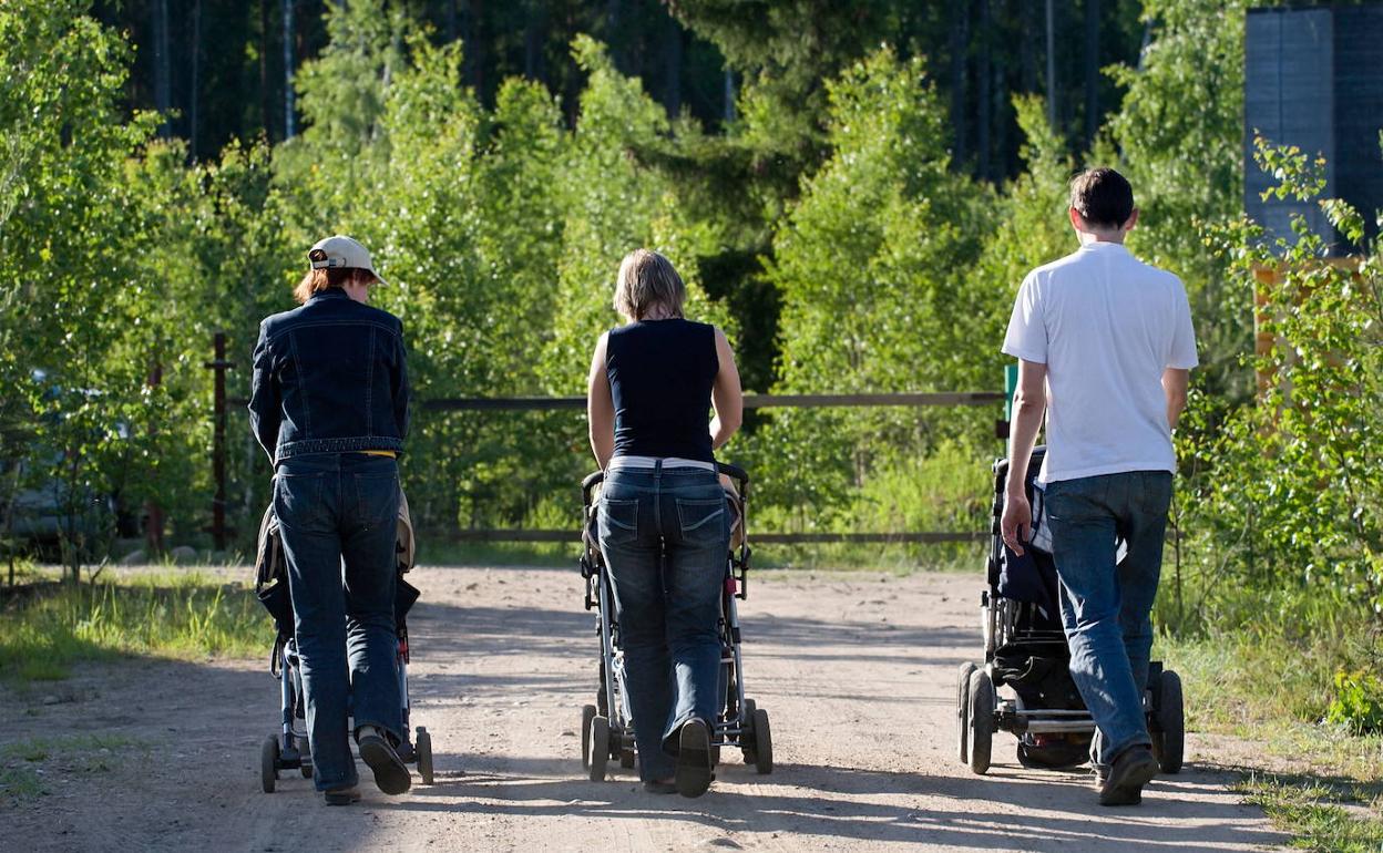 Tres personas pasean con sus bebés. 