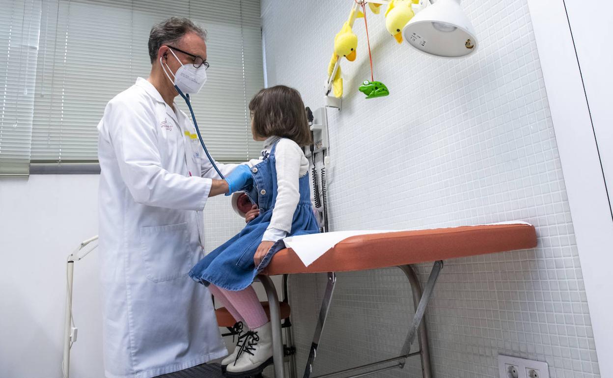 Un pediatra ausculta a una niña en la consulta. 