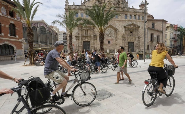 Un grupo de ciclistas pasa por delante de la iglesia de los Santos Juanes. 