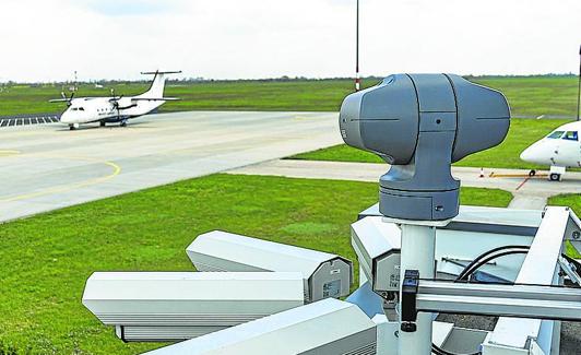 Torre erizada de cámaras junto a la pista de rodadura. Abajo, aeropuerto internacional de Budapest, donde la compañía española Indra ha implementado un sistema remoto que será operativo en un año.