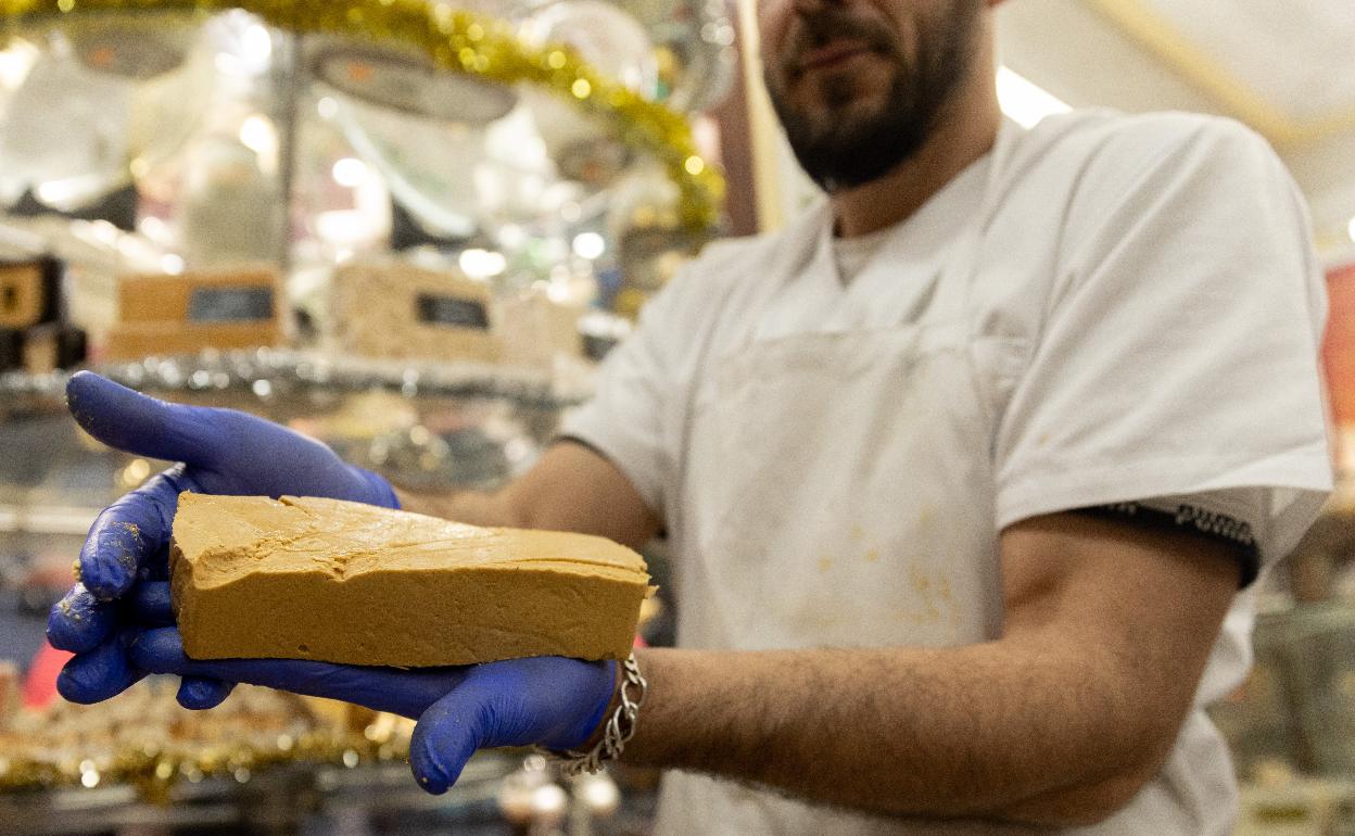 Un pastelero sostiene una tableta de turrón. 