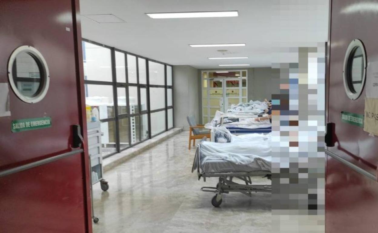 Pacientes en pasillo que une el servicio de Urgencias y las Consultas Externas del hospital de La Ribera, sin cortinas ni tomas de oxígeno.