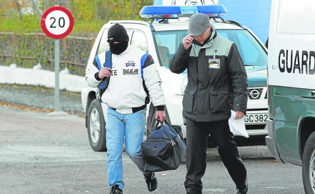 Miguel Ricart, con el rostro cubierto, junto a un funcionario al abandonar la cárcel de Herrera de La Mancha en noviembre de 2013. 