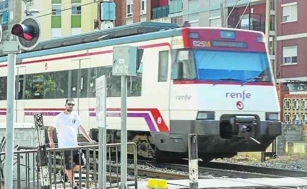 Un tren cruza por el paso a nivel de Alfafar. 