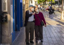 Dos ancianos con mascarilla paseando por la calle