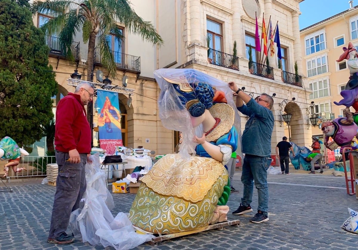 Dos artistas desembalan un ninot de la Falla Mercat de Gandia.