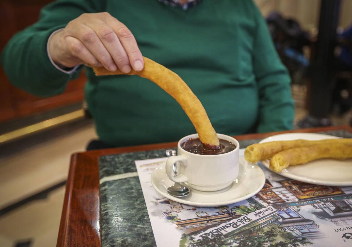 Un hombre come churros con chocolate