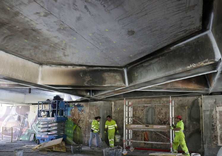 Operarios trabajando en la parte inferior del puente de las Flores, donde se produjo el incendio.